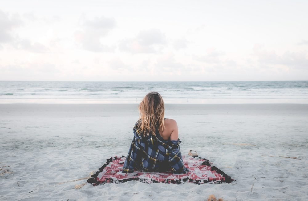 Uma mulher de costas no mar, sentindo a leveza e a calma.