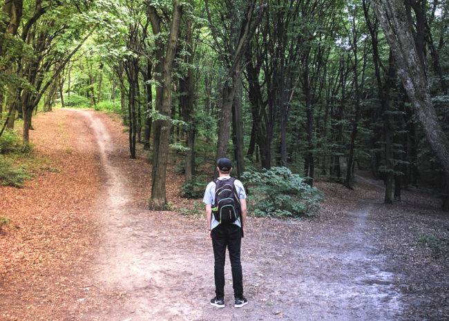 Um homem entre dois caminhos, ele está em dúvida de qual optar.